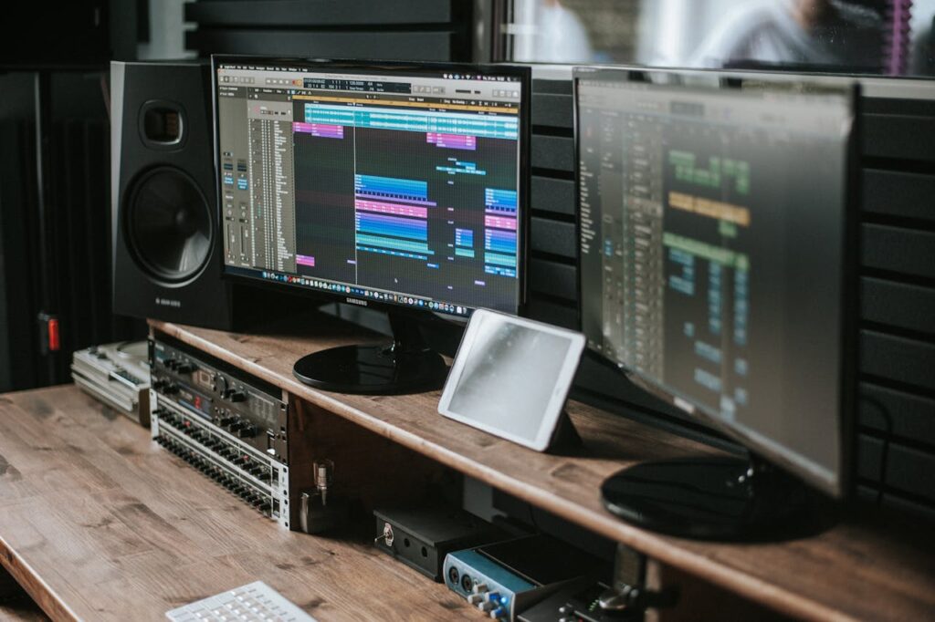 pexels photo 11044812 Modern music studio setup featuring dual monitors displaying audio editing software on a wooden desk.
