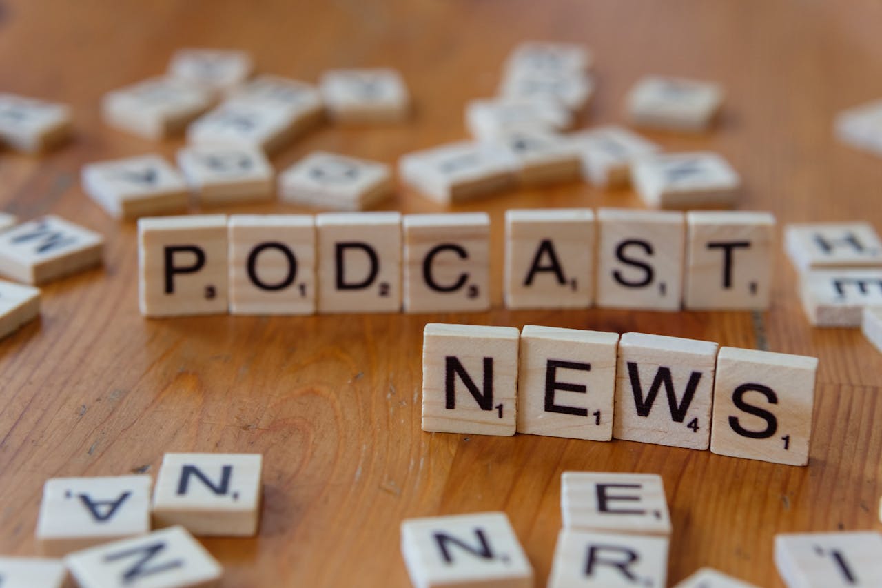 gallery-4 Wooden letter tiles spelling out 'PODCAST NEWS' on a wooden surface.